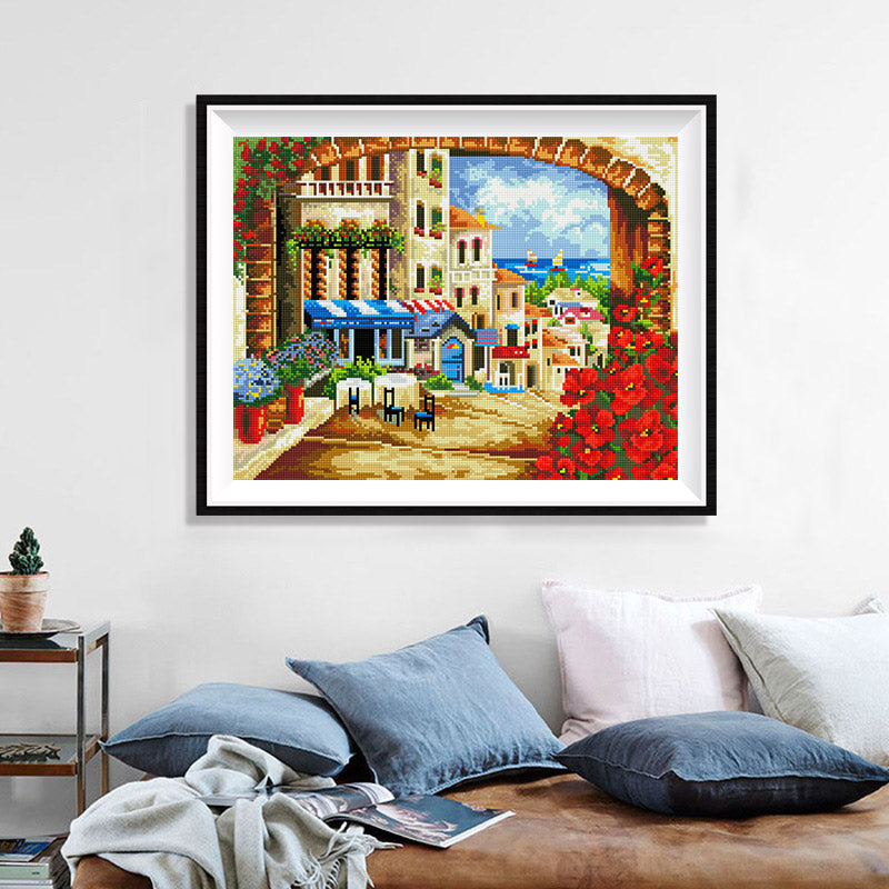 Mediterranean Arch View Diamond Painting Kit – Stone Arch Framing Coastal Town with Café, Red Poppies & Sea Beyond JX101